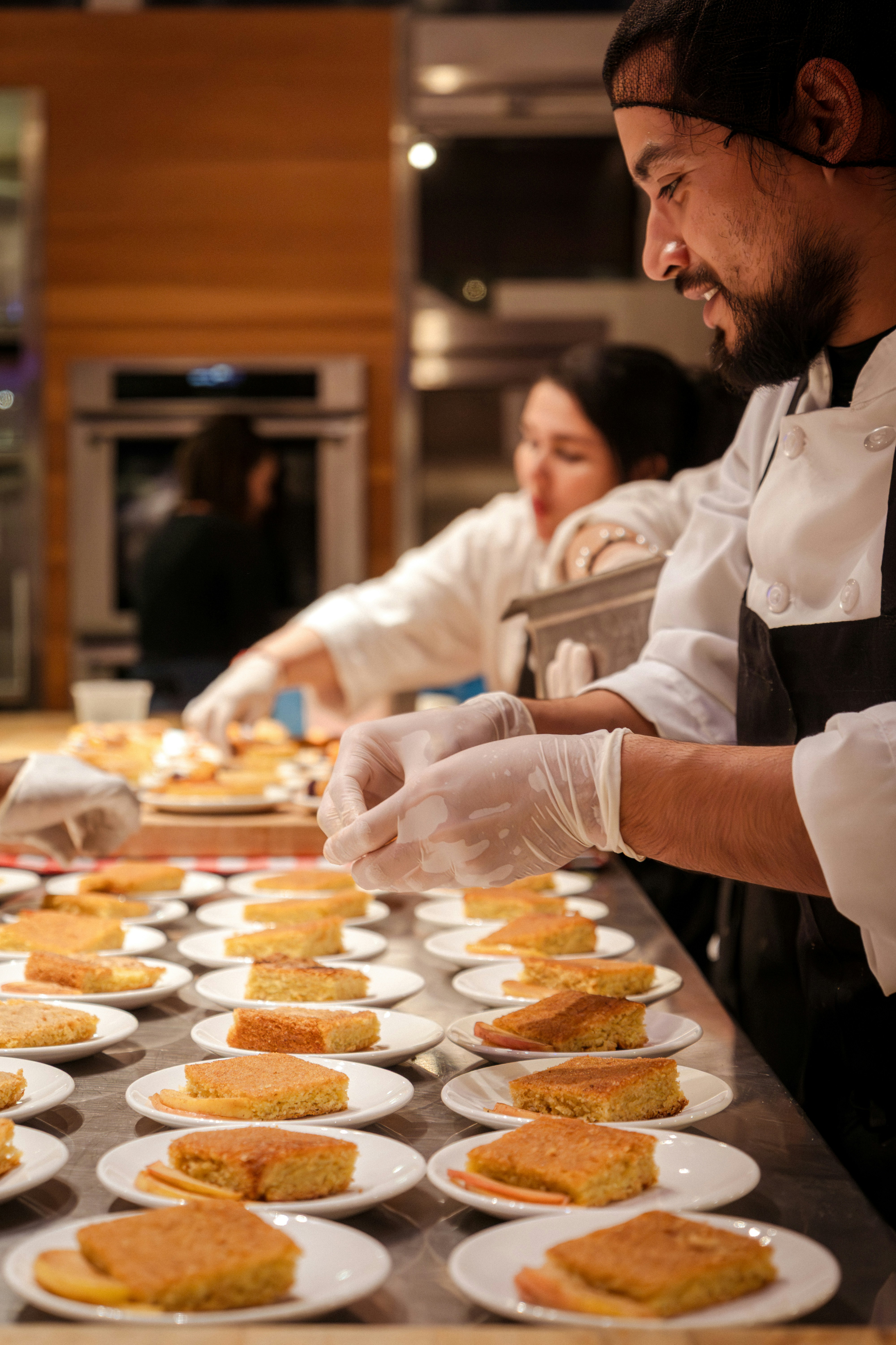 Chefs plating dishes together in a restaurant kitchen